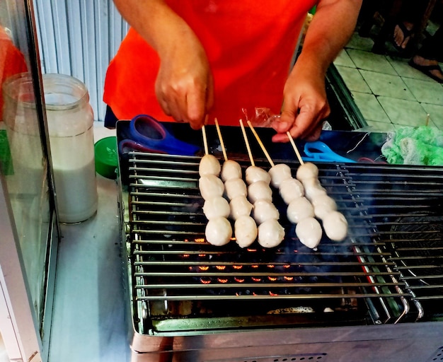 Vrouw die geroosterde varkensvleesballen op de elektrische grill draait