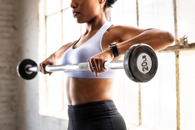 Vrouw die gewichtheffen met barbell uitoefent bij fitness gym