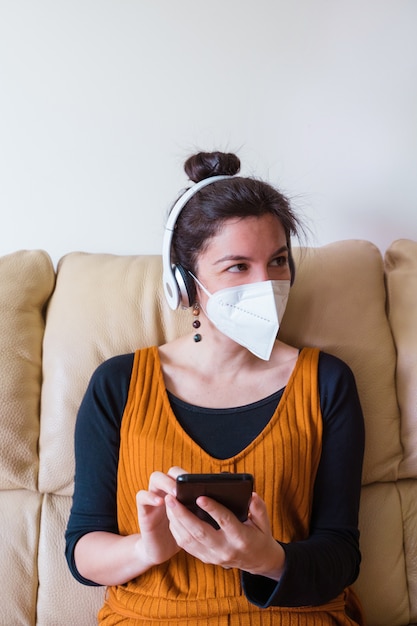 Vrouw die gezichtsmasker draagt dat een vriend thuis roept. mensen die besmet zijn met coronavirusziekte op de bank thuis. blijf thuis. pandemische virusziekte covid 19.