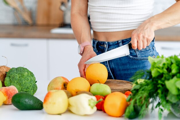 Vrouw die Gezond voedsel in Keuken voorbereiden. Sinaasappelen snijden. Gezond eten concept. Veganisten en vegetariërs. Detailopname. Fruit en groenten.