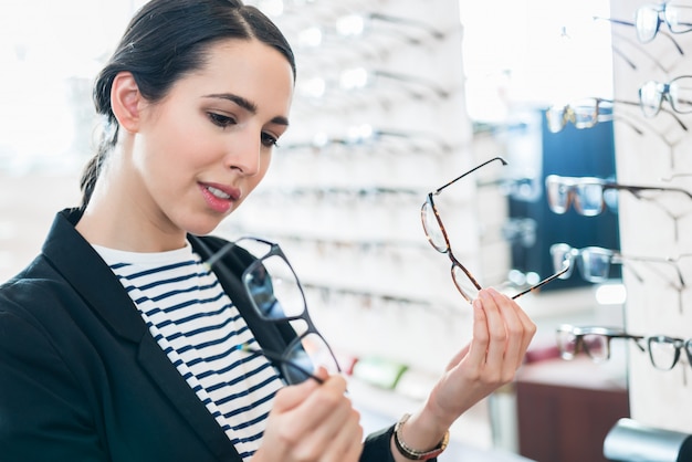 Vrouw die glazen vergelijkt bij opticien