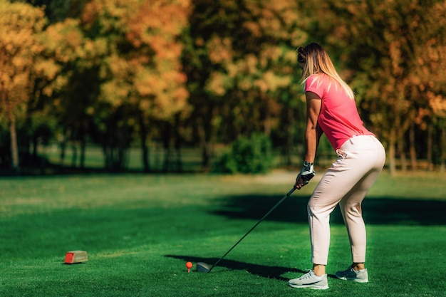 Vrouw die golf speelt en zich klaarmaakt voor het schot