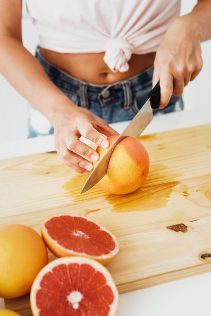 Vrouw die grapefruits snijdt op snijplank voor zelfgemaakt vers sap