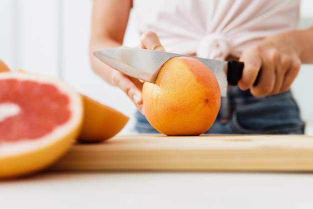 Vrouw die grapefruits snijdt op snijplank voor zelfgemaakt vers sap