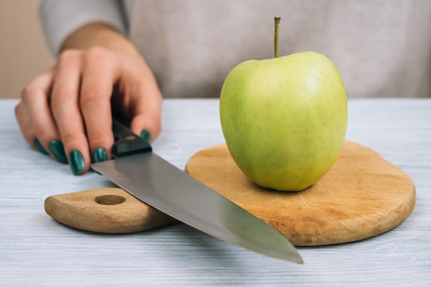 Vrouw die groene appel met een keukenmes gaat snijden