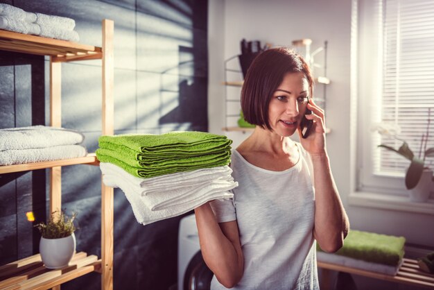 Vrouw die groene gevouwen handdoeken houdt en op telefoon spreekt