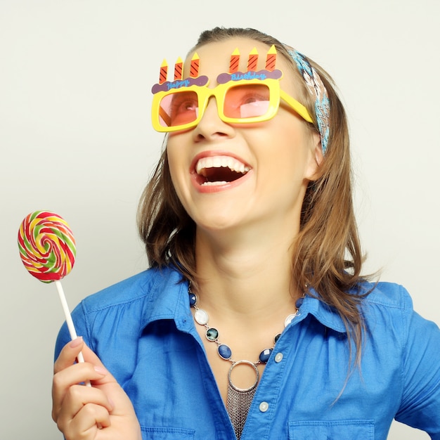 Vrouw die grote zonnebril draagt die lolly houdt