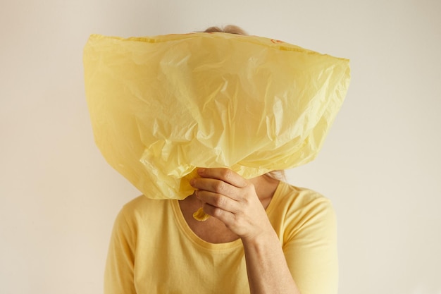 Foto vrouw die haar gezicht bedekt met geel plastic zak ecologisch concept