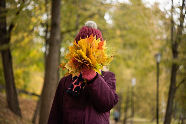 Vrouw die haar gezicht behandelt met veel de herfstbladeren