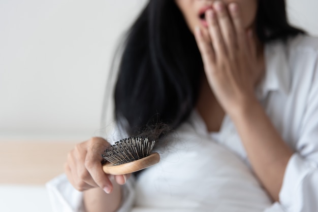 Vrouw die haar haar voor het probleem van het haarverlies bekijkt