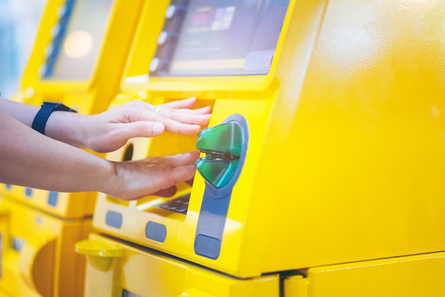 Vrouw die haar handen behandelen terwijl het ingaan van haar PIN bij ATM