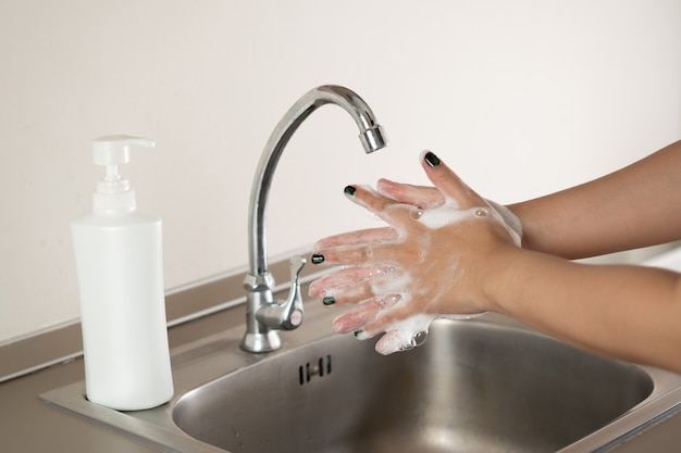 Vrouw die haar handen met zeep wast