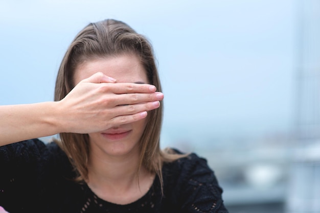 Vrouw die haar ogen met haar handen bedekt.