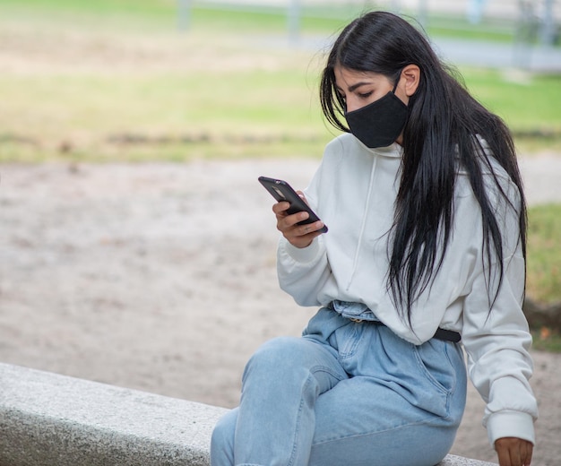 Vrouw die haar smartphone gebruikt terwijl ze een coronavirusmasker draagt