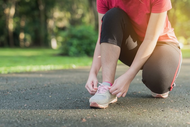 Vrouw die haar sportschoenen in het park binden