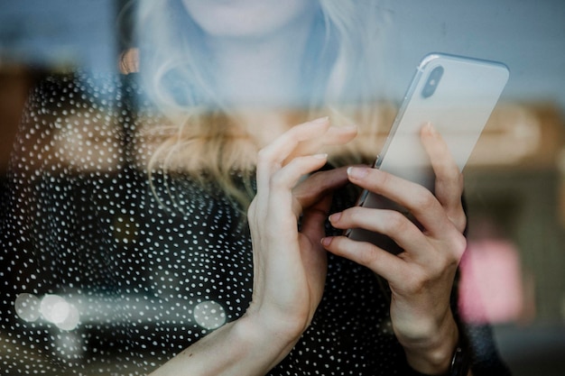 Vrouw die haar telefoon gebruikt in een café