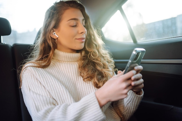 Vrouw die haar telefoon gebruikt tijdens Traveling in Car Chats terwijl ze in Taxi Business concept rijdt