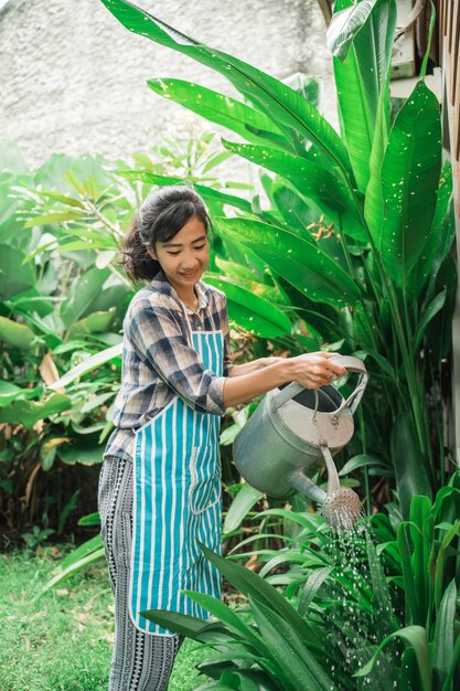 Vrouw die haar tuin thuis water geeft