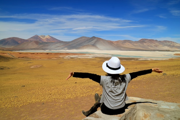 Vrouw die haar wapens opheft voor de zoute meren van Salar de Talar en de berg Cerro Medano, Chili