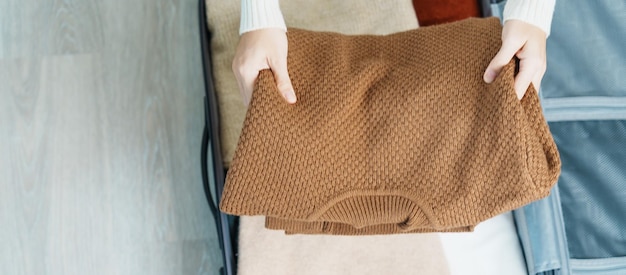 Vrouw die haar winterkleren met de hand in bagage inpakt tijd om te reizen reis ontspan lente of herfst of winterseizoen en vakantieconcepten