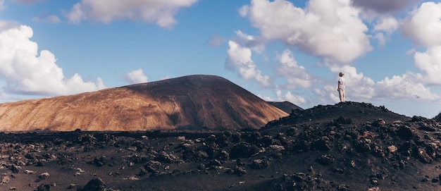 Vrouw die handen in de lucht opstijgt en geniet van een prachtig uitzicht op het vulkanische landschap in timanfaya national