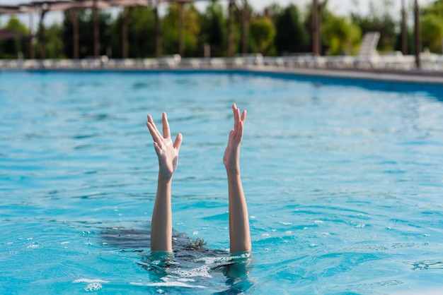 Vrouw die handen omhoog in pool opheft