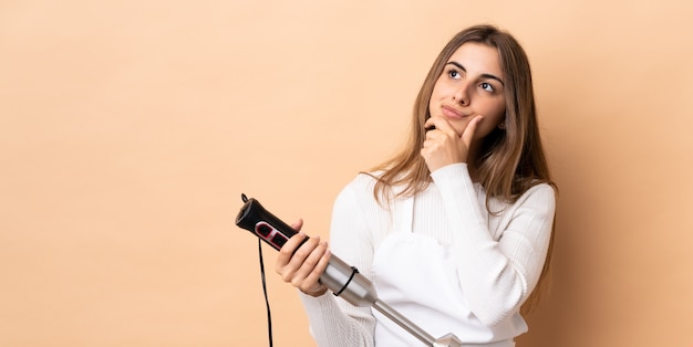 Vrouw die handmixer gebruikt die twijfels heeft