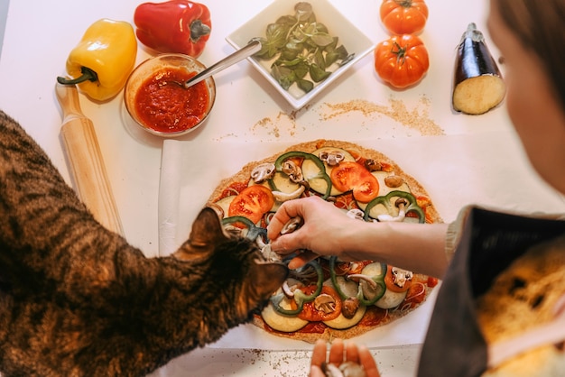 Vrouw die heerlijke pizza bereidt met haar lieve kat. Zelfgemaakt concept.
