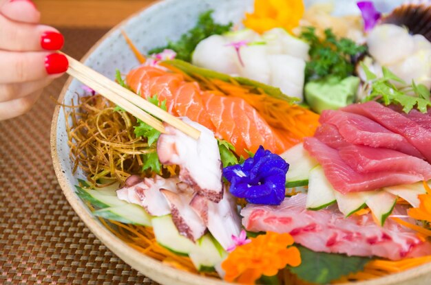 Vrouw die heerlijke sashimi close-up op eetstokjes eet