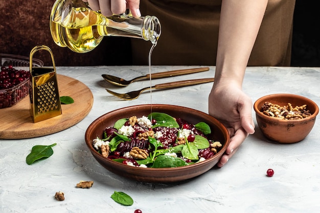 Vrouw die heerlijke superfoodsalade mengt met bieten verse babyspinazie kaas noten veenbessen Schoon eten dieet veganistisch voedselconcept Achtergrond voedselrecept Close-up