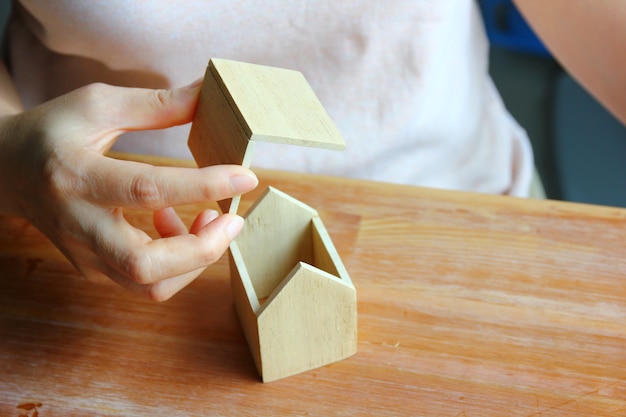 Vrouw die het dak van een houten modelwoning installeert