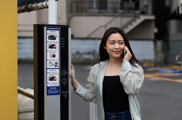 Foto vrouw die het laadstation voor elektrische auto's gebruikt