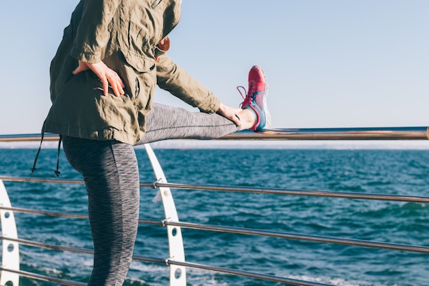 Vrouw die het uitrekken zich in de ochtend op de kust doet