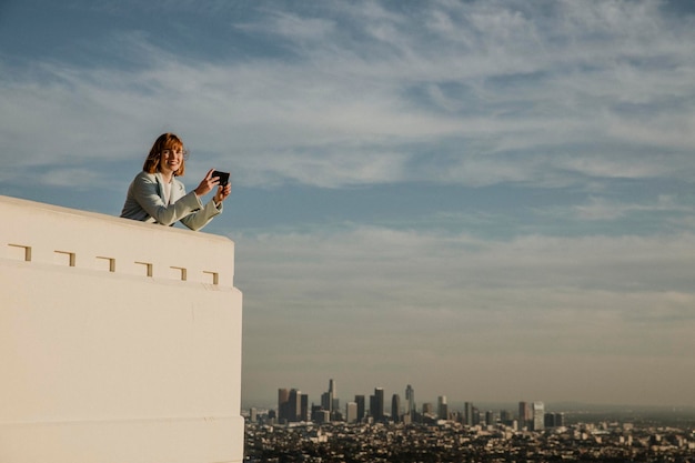 Vrouw die het uitzicht op Los Angeles vastlegt met haar telefoon bij het Griffith Observatory, VS