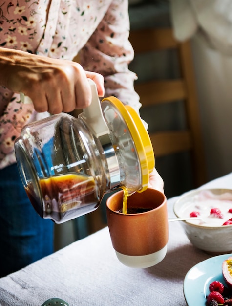 Vrouw die hete koffie voor het ontbijt serveert