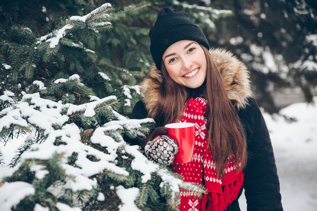 Vrouw die hete thee in het de winterbos drinkt