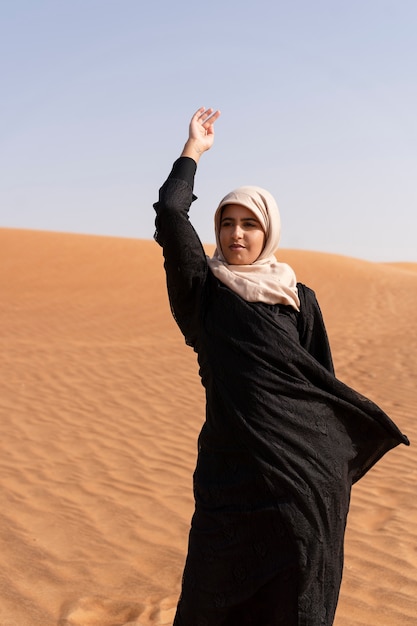 Foto vrouw die hijab draagt in de woestijn