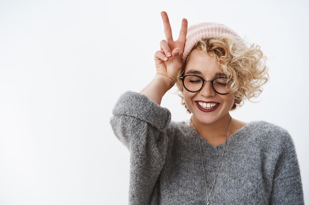 vrouw die houdt van winter en vakanties die plezier heeft, zich gelukkig en teder voelt ogen sluiten vreugdevol muts en trui dragend glimlachend in het algemeen vrede tonend