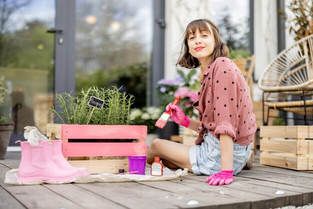 Vrouw die houten kist schildert, doet wat huishoudelijk werk buitenshuis