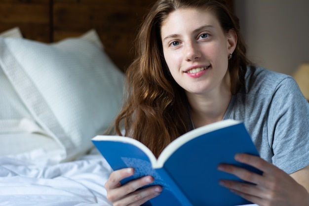 Vrouw die in bed legt en boek leest