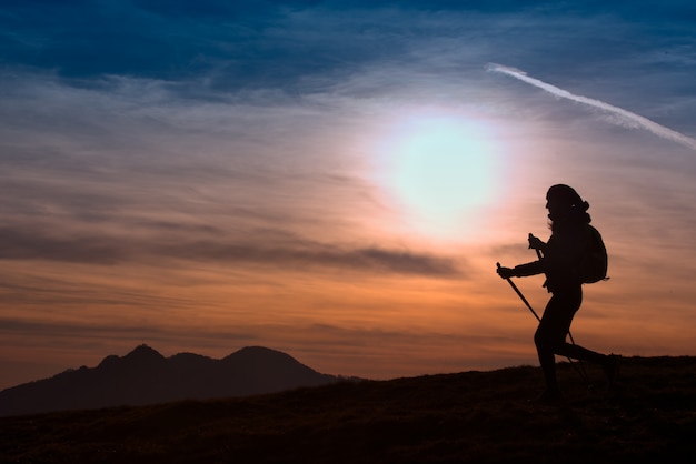 Vrouw die in de bergen bij zonsondergang wandelt