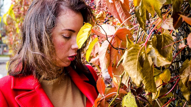 Foto vrouw die in de herfst bij een plant in de tuin staat