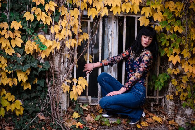 Foto vrouw die in de herfst bij gele bladeren staat