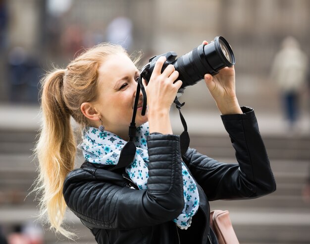 vrouw die in de herfststad loopt met digitale camera