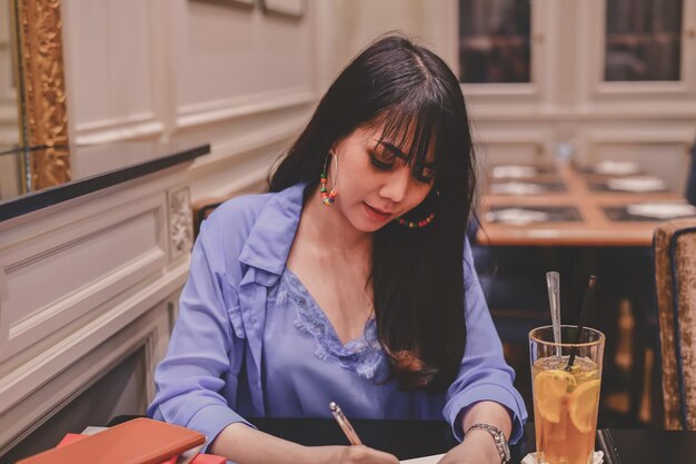 Vrouw die in een dagboek schrijft terwijl ze in een restaurant zit
