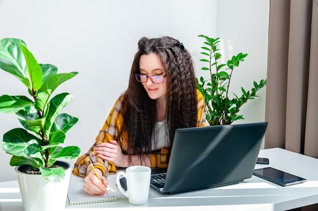 Vrouw die in een notitieboekje schrijft Vrouw die thuis werkt, maakt aantekeningen tijdens een vergadering in opleiding