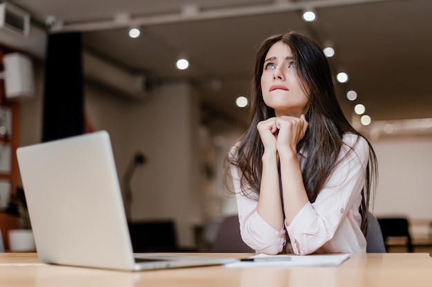 Vrouw die in het bureau werkt en en hoopt en bidt