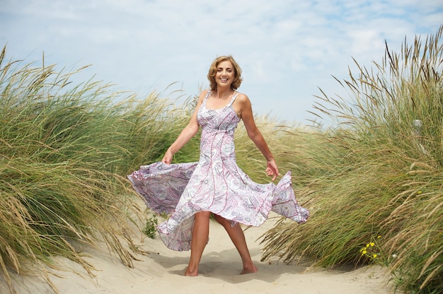 Foto vrouw die in het zand bij het strand danst