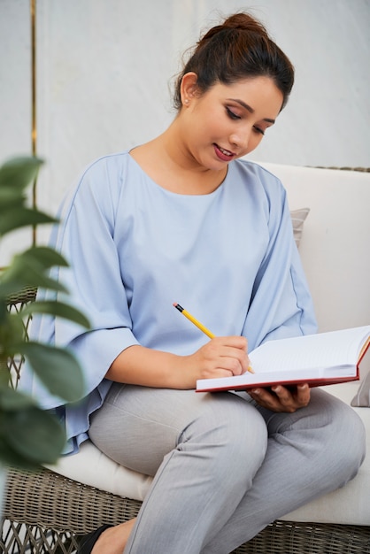 Vrouw die in kladblok schrijft