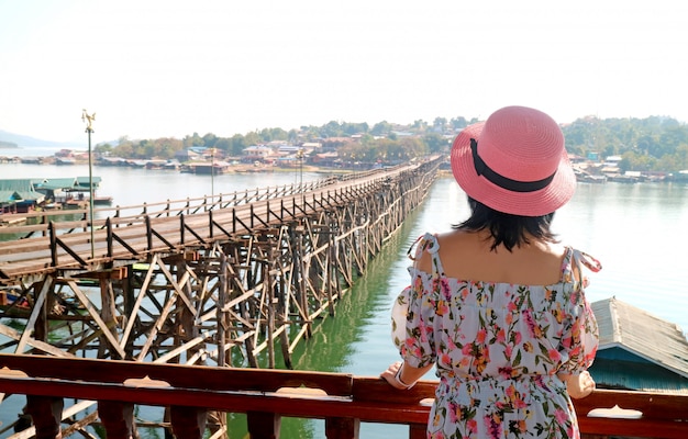 Vrouw die in Roze Hoed de Mon-Brug, Oriëntatiepunt van Sangkhlaburi-District, Thailand bewonderen